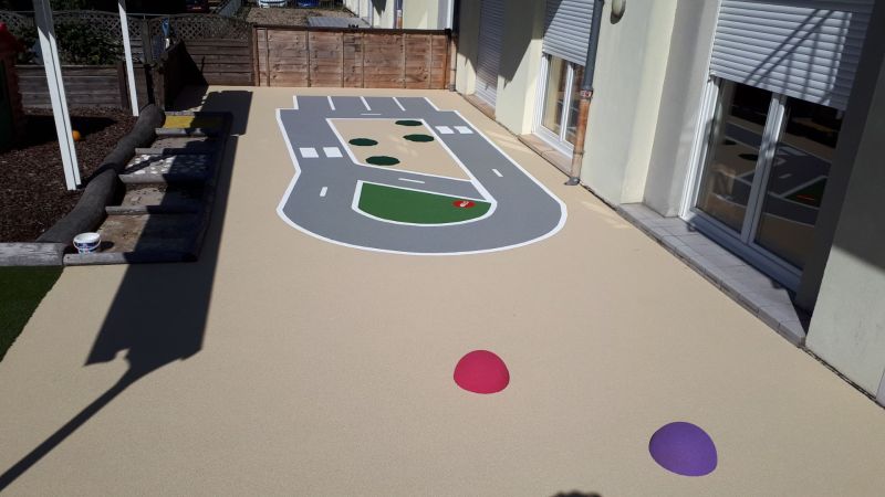 Création d’une piste cyclable pour enfants en sol coulé – aire de jeu sécurisée et durable pour apprentissage du vélo